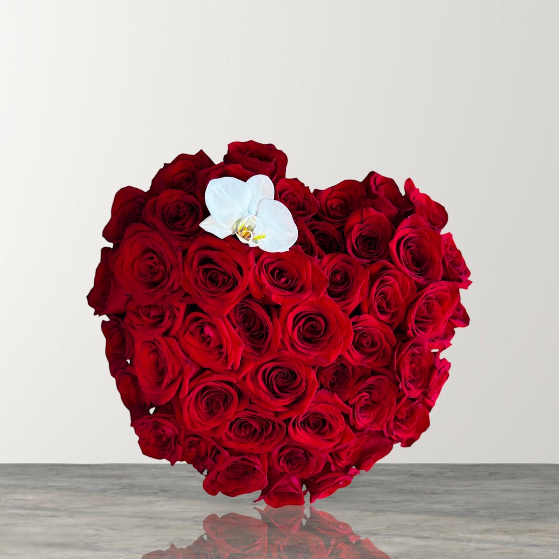 Skye Rose Floral heart-shaped box filled with deep red roses and a single white orchid for a romantic gift.