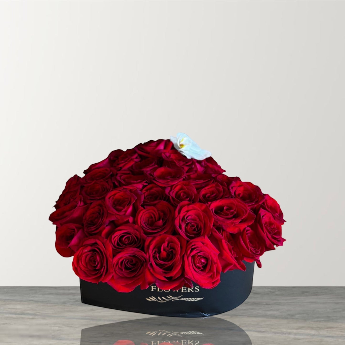 Skye Rose Floral heart-shaped box filled with deep red roses and a single white orchid accent