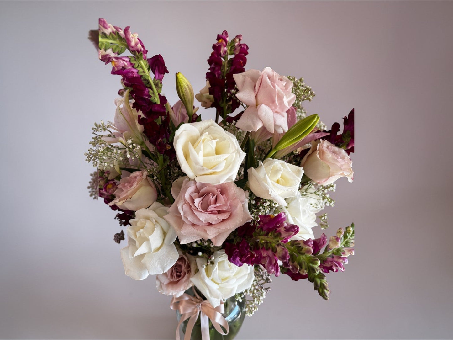 Skye Rose Floral Sophisticated Mauve bouquet with cream and dusty mauve roses and burgundy snapdragons in a vase.