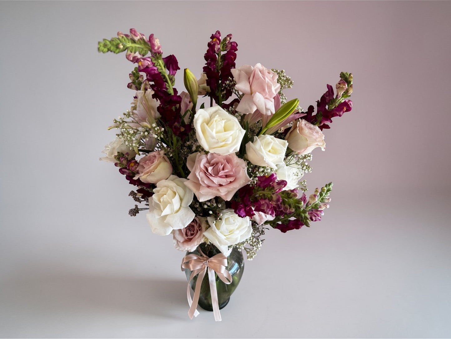 Skye Rose Floral Sophisticated Mauve bouquet with cream and dusty mauve roses and burgundy snapdragons in a vase.