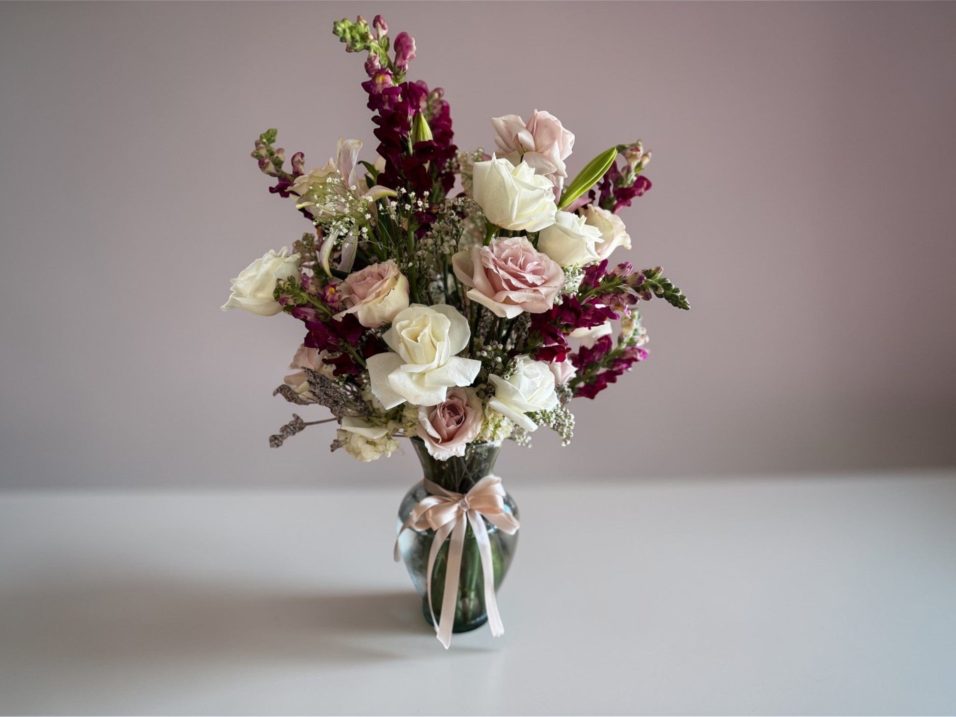 Skye Rose Floral Sophisticated Mauve bouquet with cream and dusty mauve roses and burgundy snapdragons in a glass vase