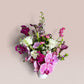 Skye Rose Floral Plum Essence arrangement featuring pink orchids, white roses, and calla lilies in a white vessel.